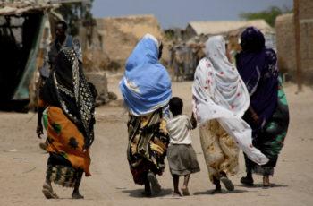 Aikuisia ja lapsi takaa päin kuvattuna kävelemässä ulkona Somalimaassa.