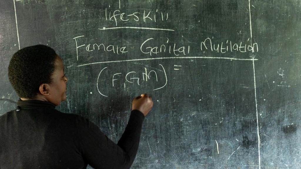 Nainen kirjoittaa Female Genital Mutilation liitutaululle