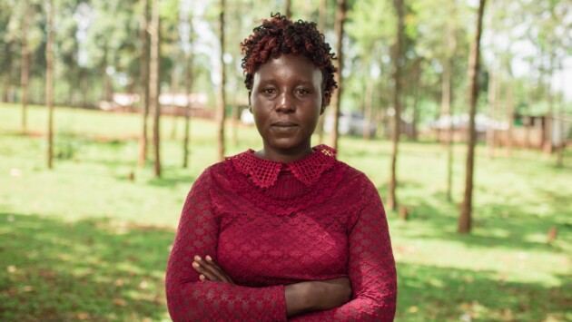 Kenialainen opettaja Esther Atoni seisoo vehreällä koulun pihalla