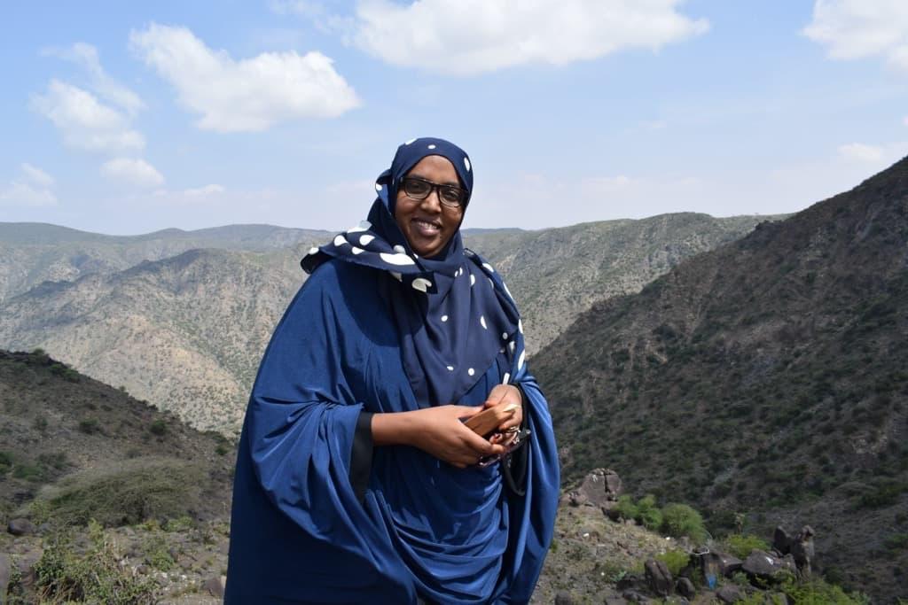 Kuvassa Solidaarisuuden somalimaalainen asiantuntija Zuhur Abdi Jama seisoo taustallaan vuoret, hymyilee ja katsoo kameraan.
